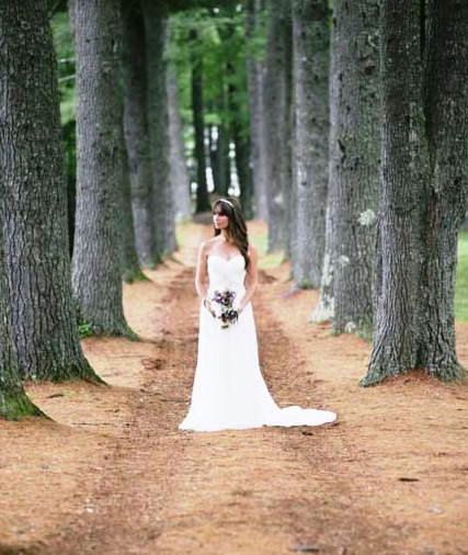 A bride poses in the woods